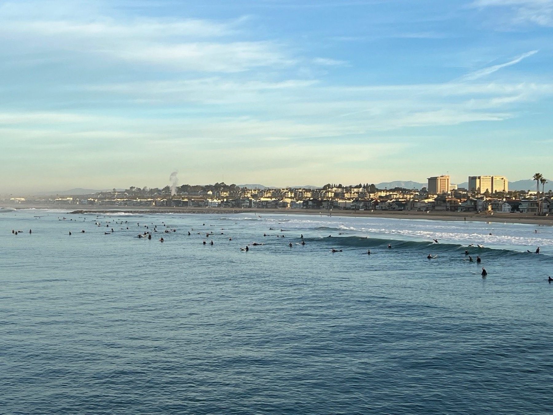 Surfers in the water off Newport Beach at golden hour
